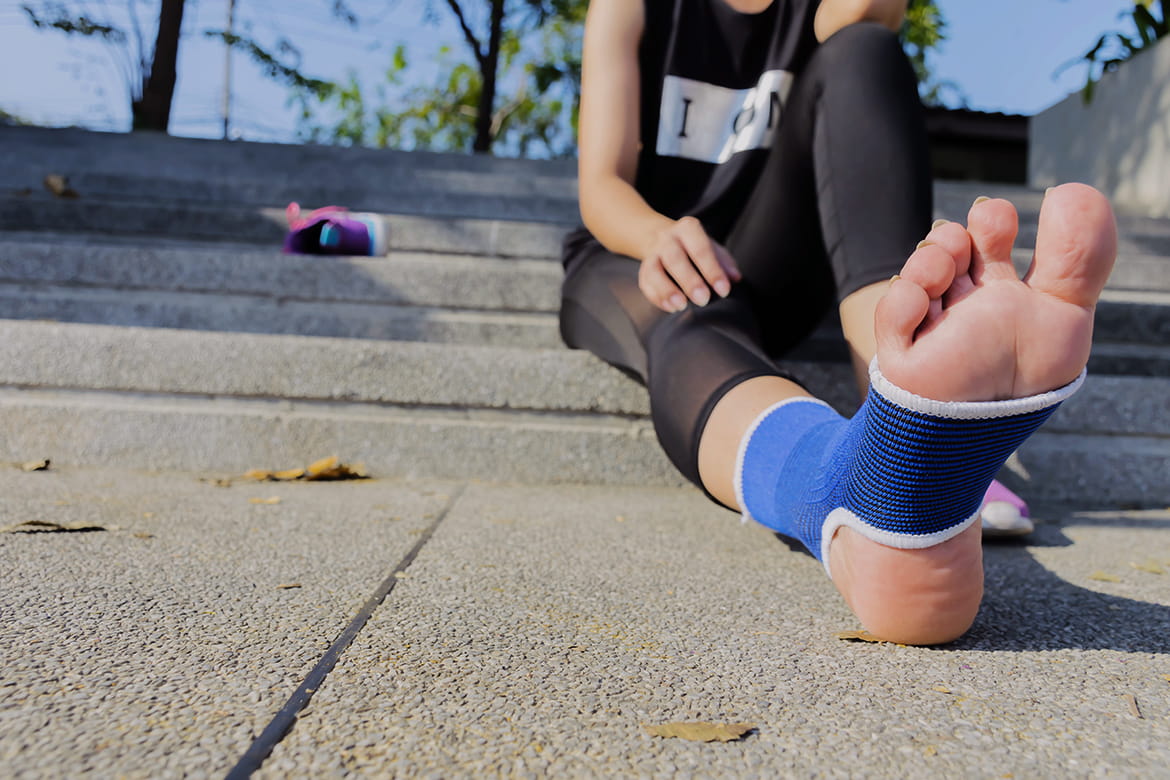 A woman sitting on steps with her foot in a cast.