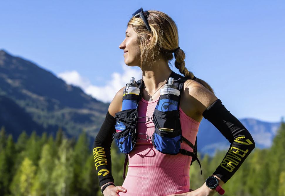 A woman is standing in front of a mountain.