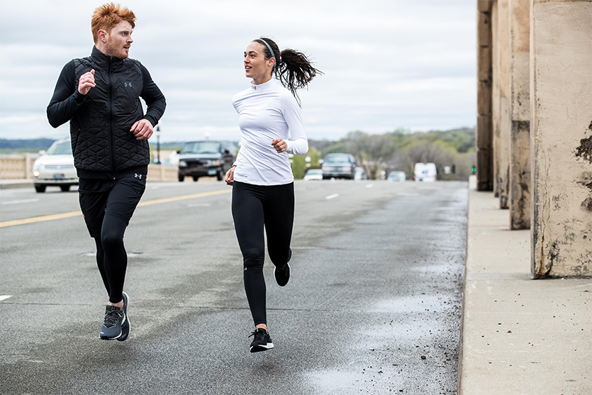 A man and woman jogging on a bridge.