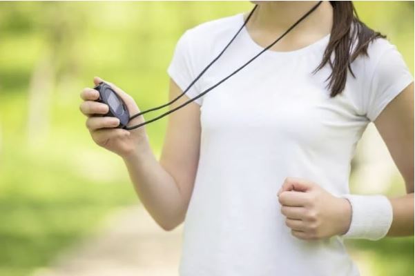 A woman holding a cell phone while running in the park.