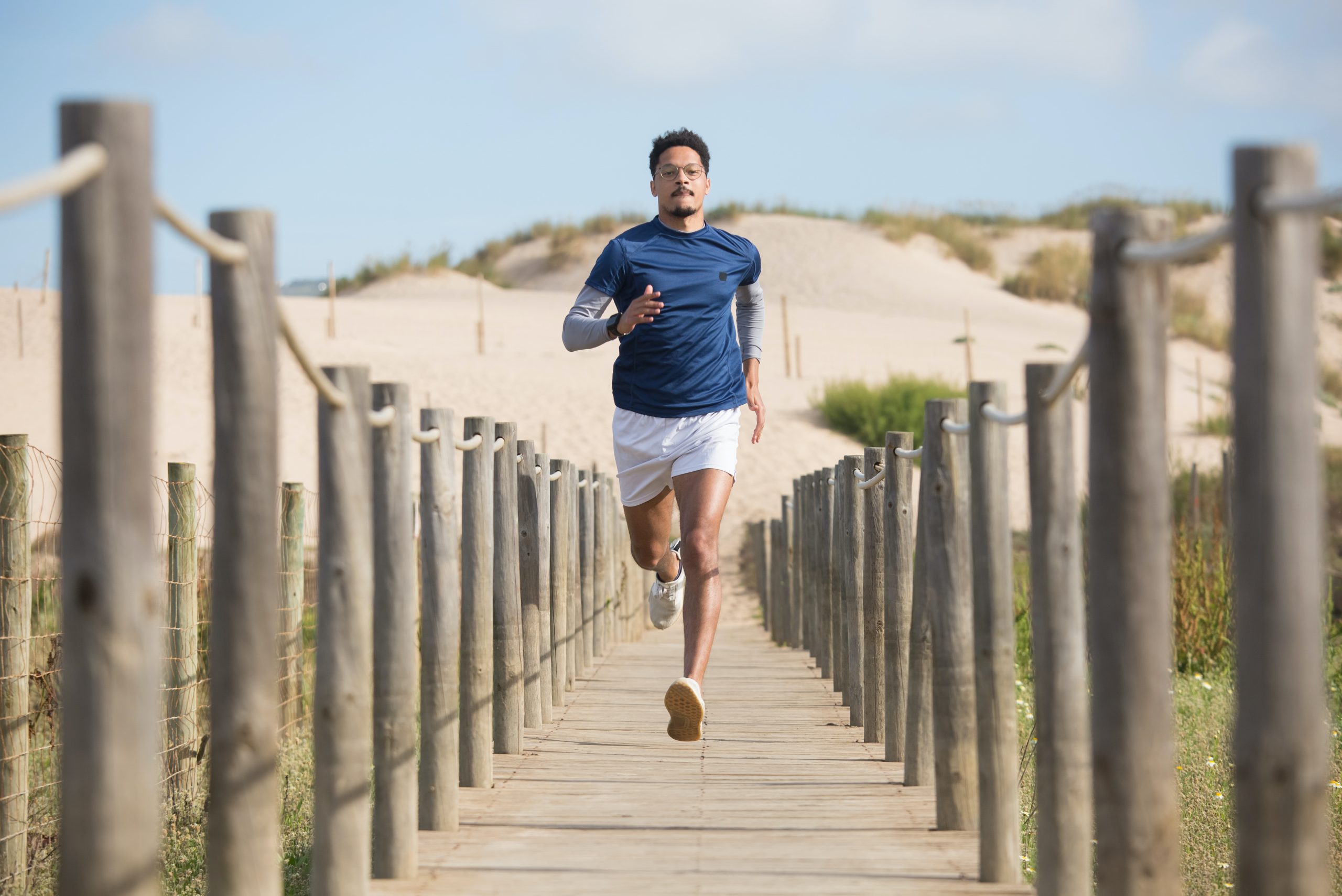 A man running on a wooden boardwalk at the beach.