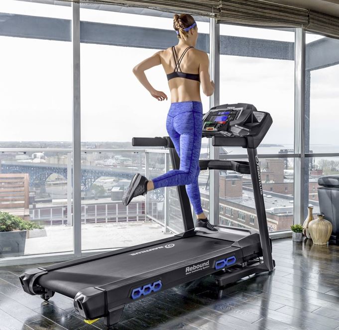 A woman is running on a tread machine.