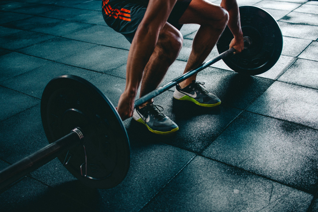 A man lifting a barbell in a gym.