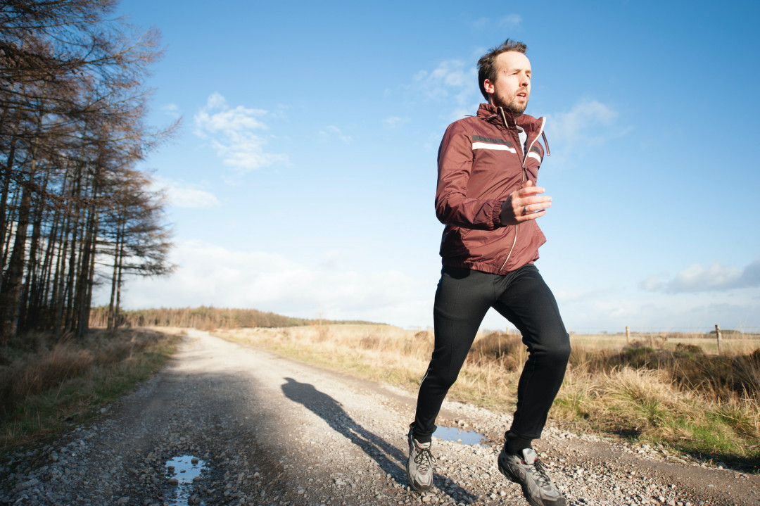 A man jogging on a dirt road.