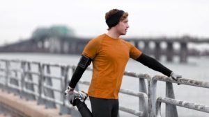 A man wearing an orange shirt is leaning against a railing.