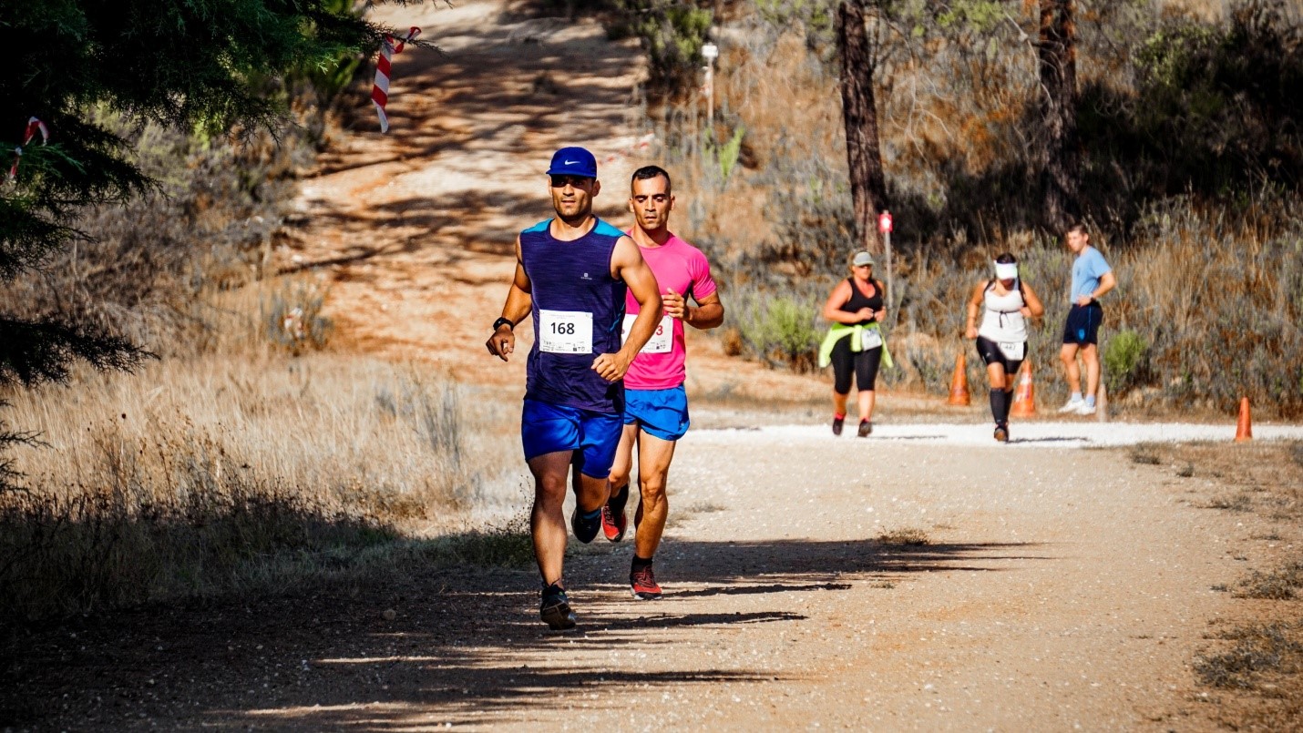 A group of people running on a trail in the woods.