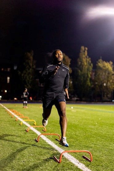 A man running on a soccer field at night.