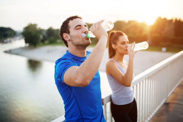 A man and woman drinking water on a bridge.