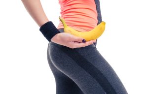 A woman is holding a banana in her stomach.