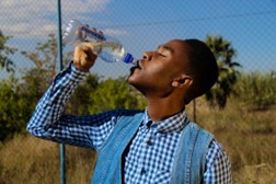 A young man drinking water from a bottle.