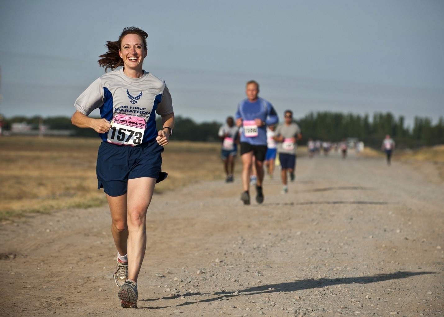 A woman running down a dirt road with other people.