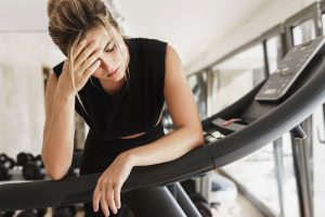 A woman is sitting on a tread machine in a gym.