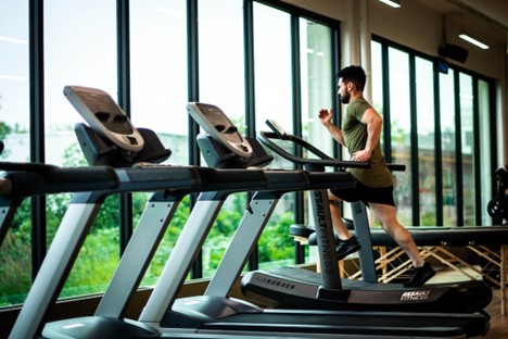 A man is running on a tread machine in a gym.