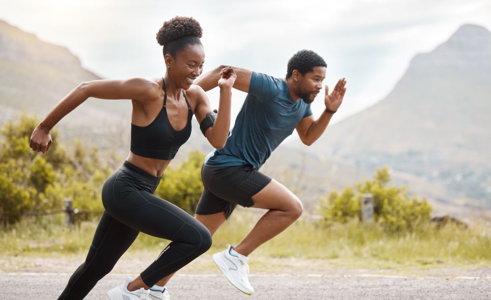 Two people running on a road with mountains in the background.