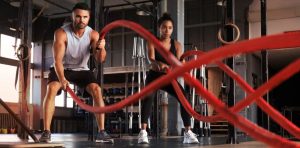 Two people working out with ropes in a gym.
