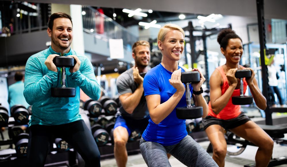 A group of people doing dumbbells in a gym.