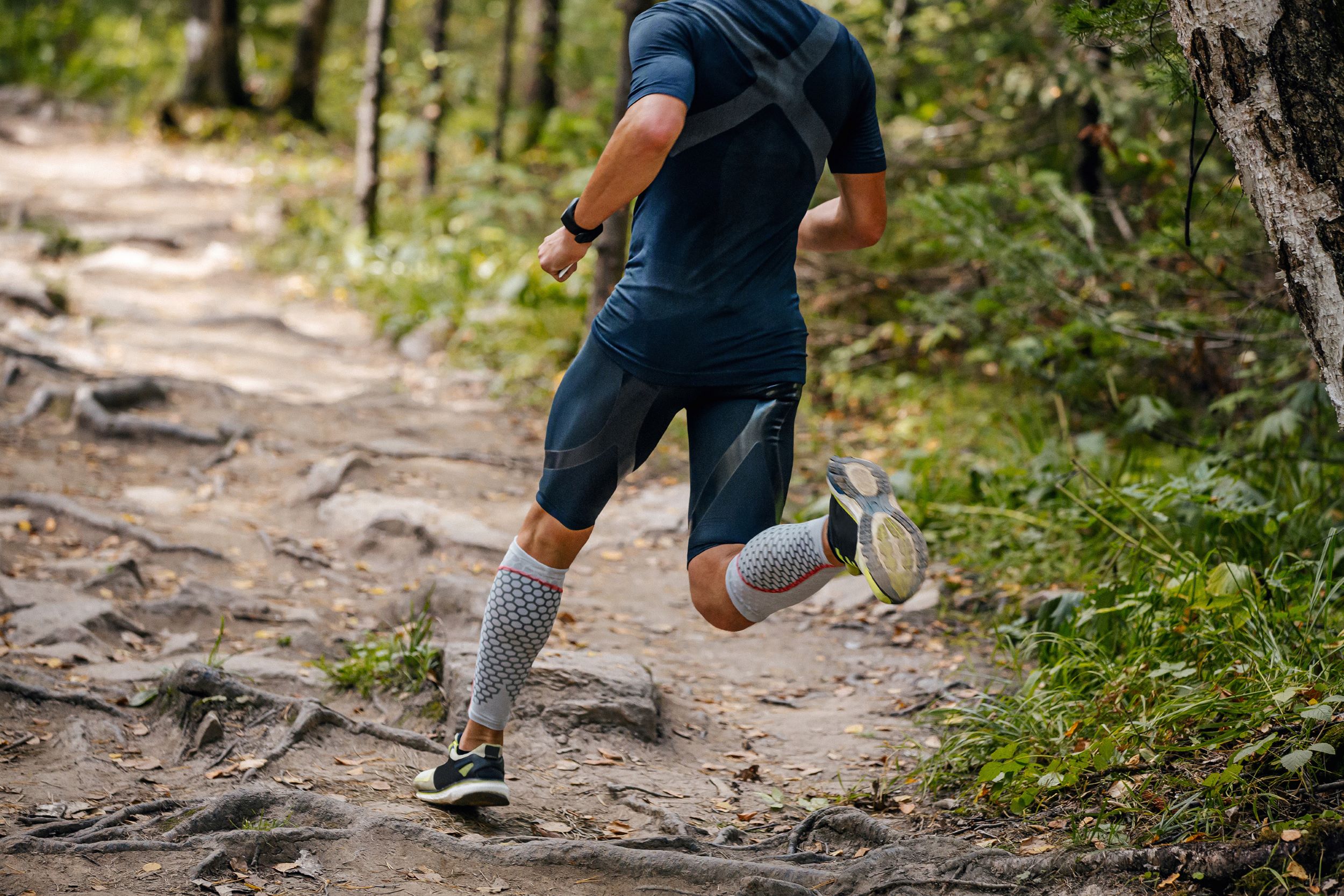 A man running on a trail in the woods.