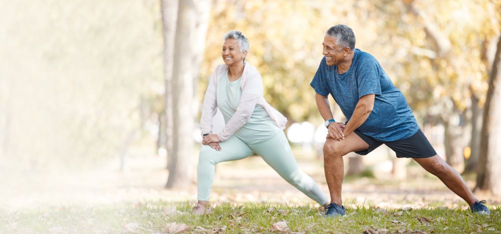 An older couple doing squats in the park.