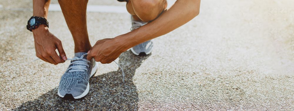 A man tying his shoes on the street.