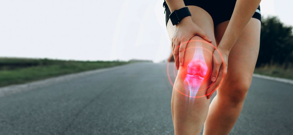 A woman with knee pain on a road.