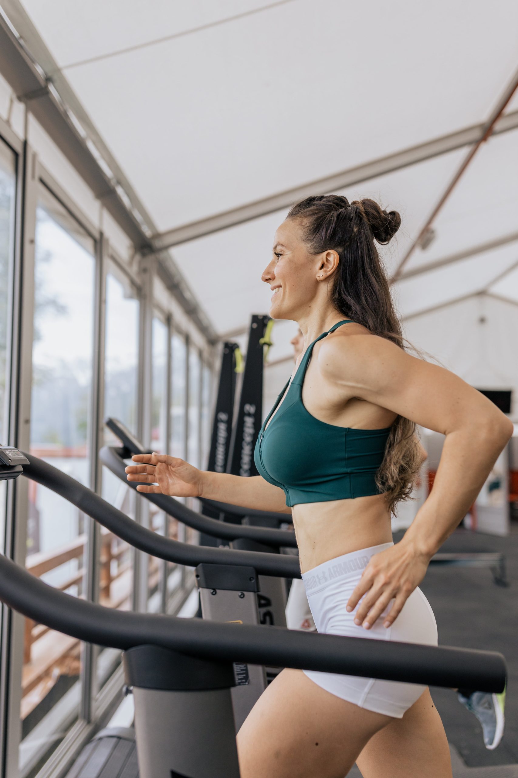 A woman is running on a tread machine in a gym.