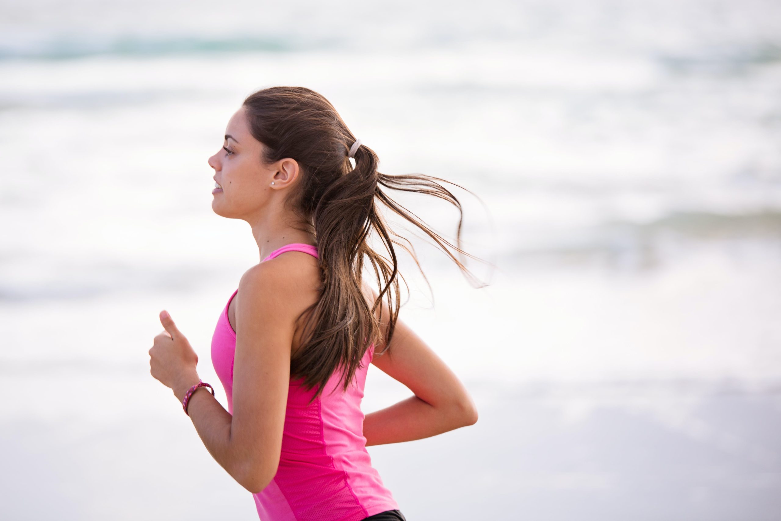A young woman jogging on the beach.