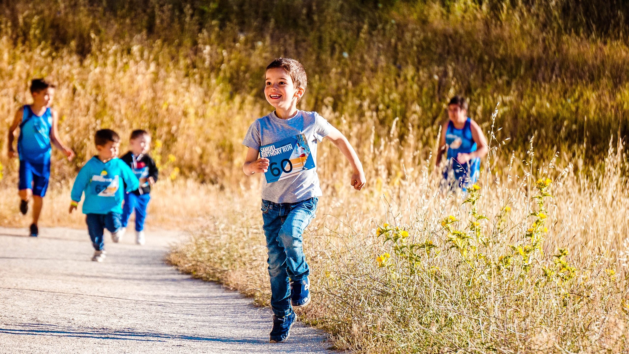 A group of children running on a path in a field.