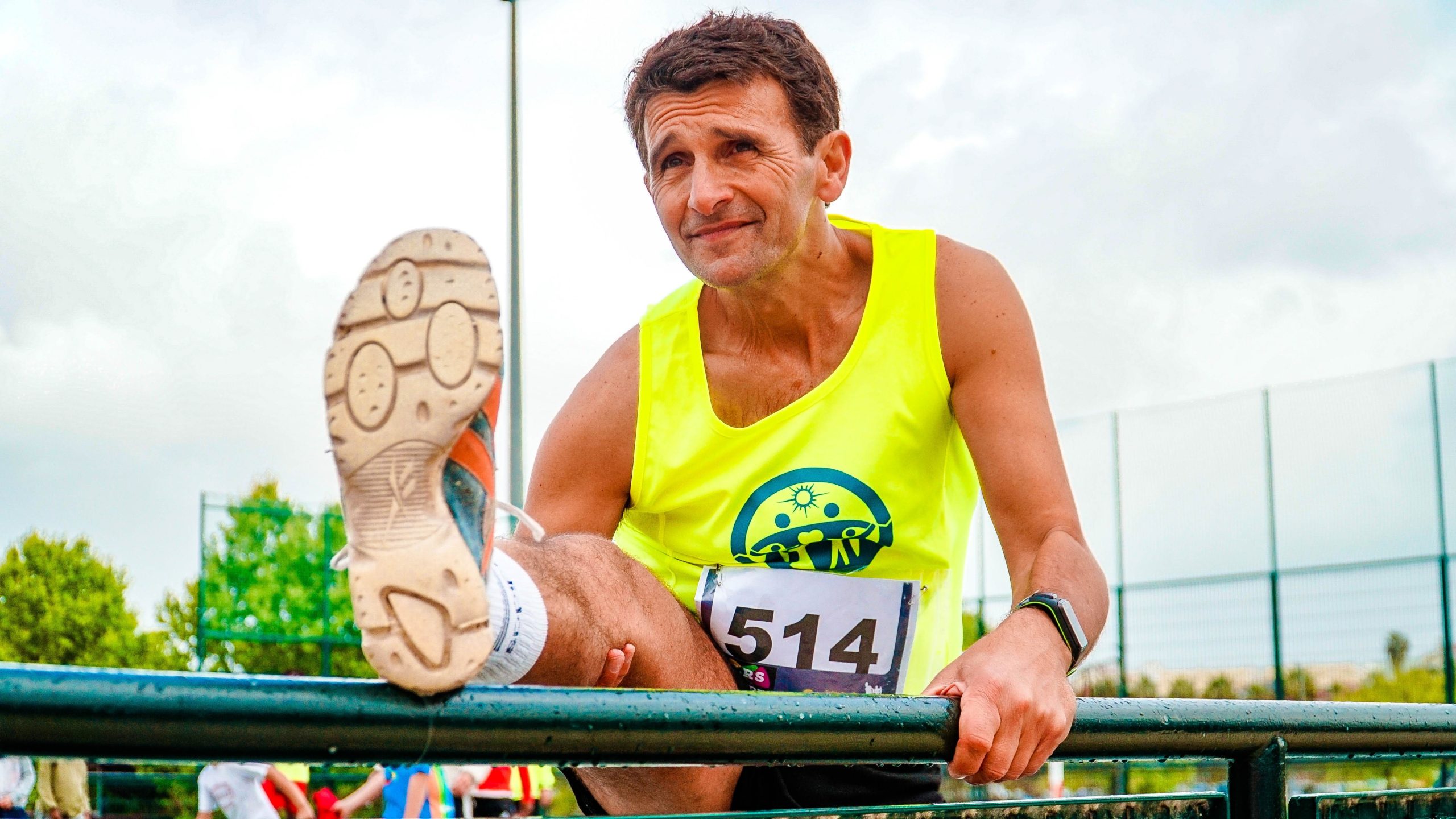 A man sitting on a railing at a race.