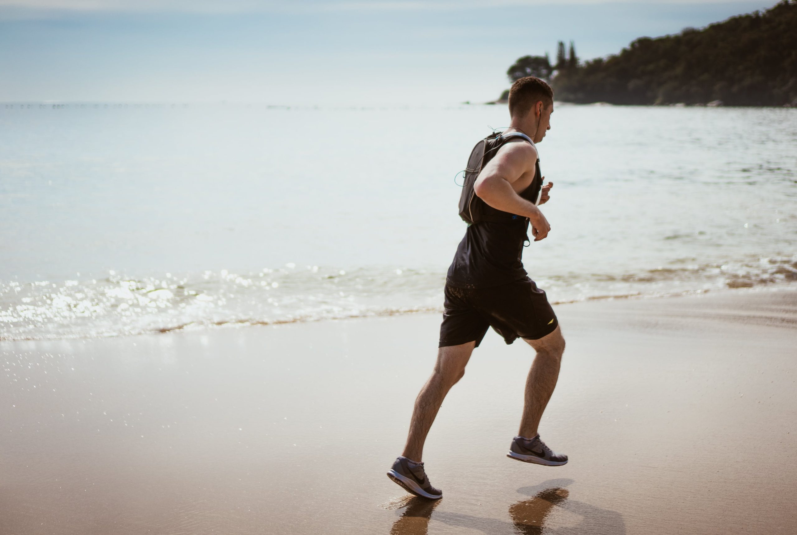 A man jogging on the beach near the ocean.
