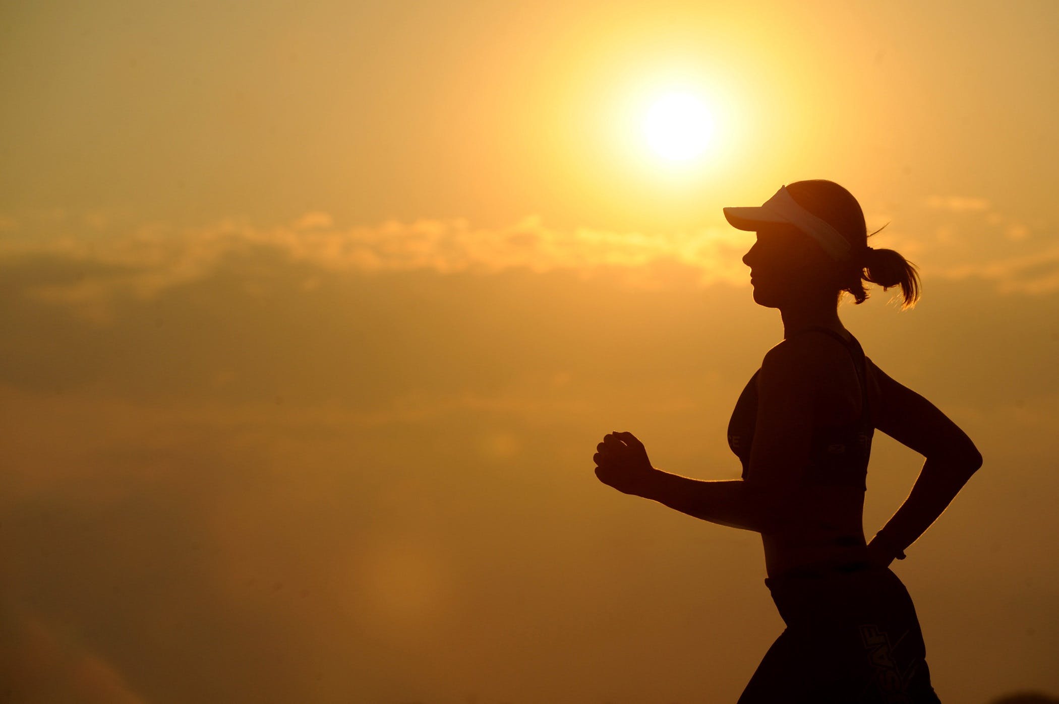 A silhouette of a woman jogging at sunset.