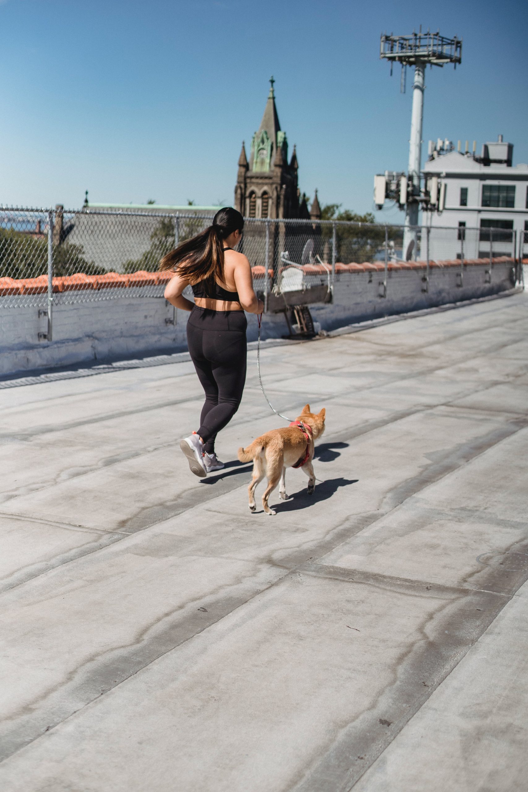 A woman running with a dog on a rooftop.