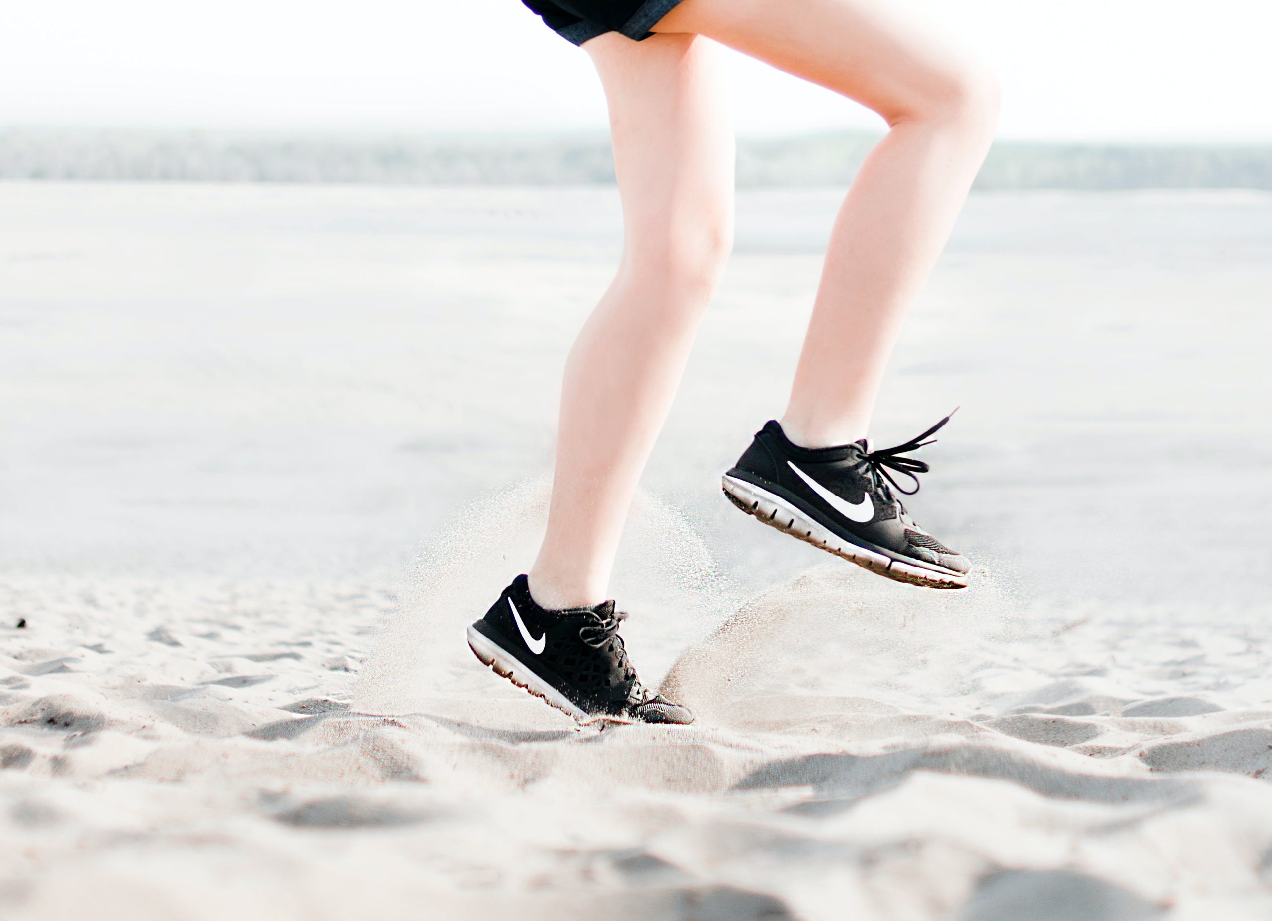 A woman in black shorts and a pair of black nike shoes.