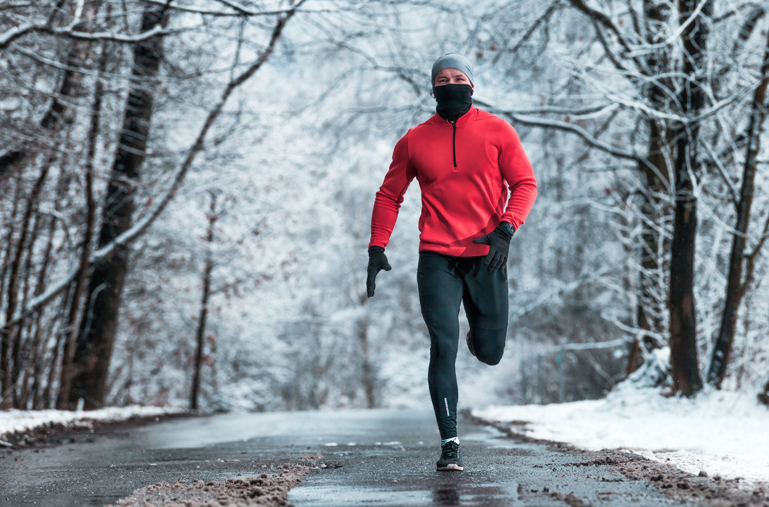 A man in a red jacket is running in the snow.