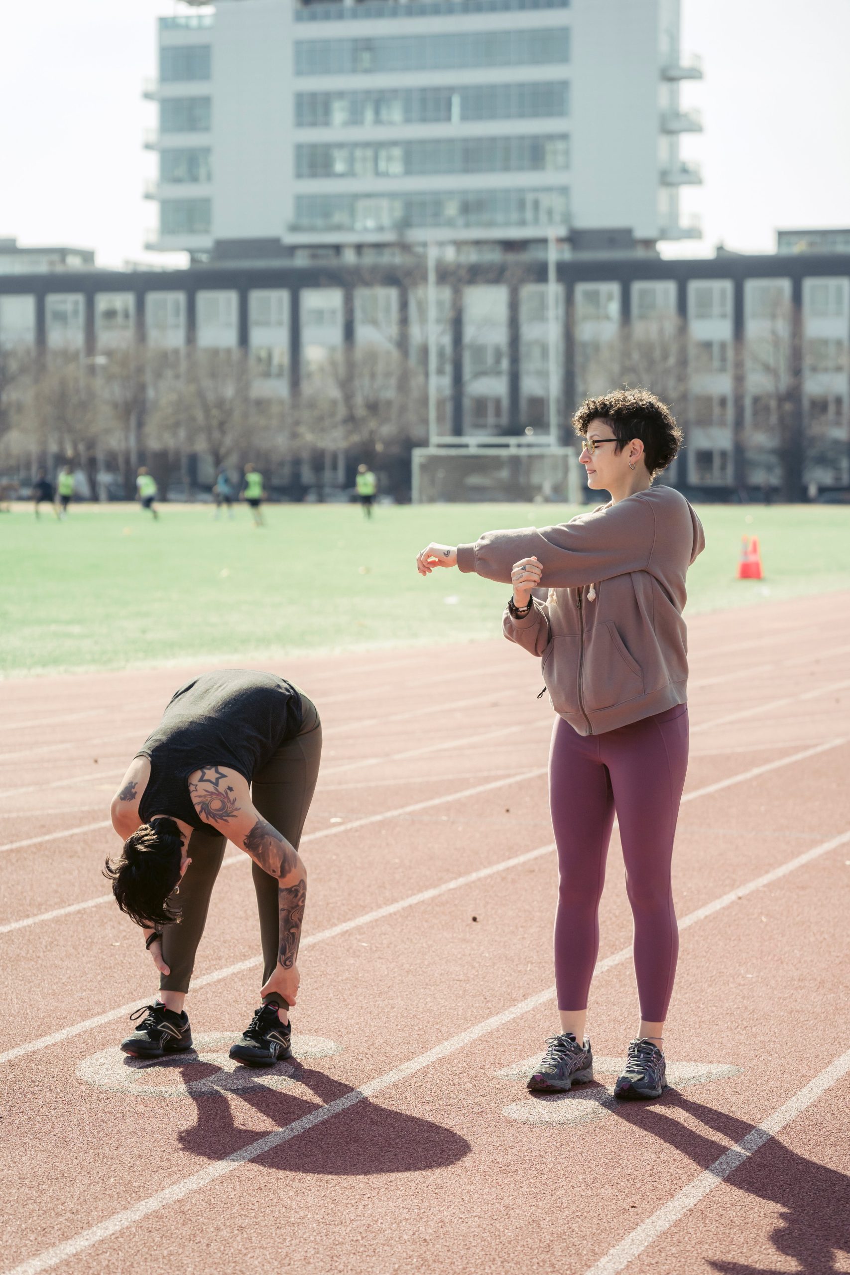 A man and woman standing on a track in front of a building.