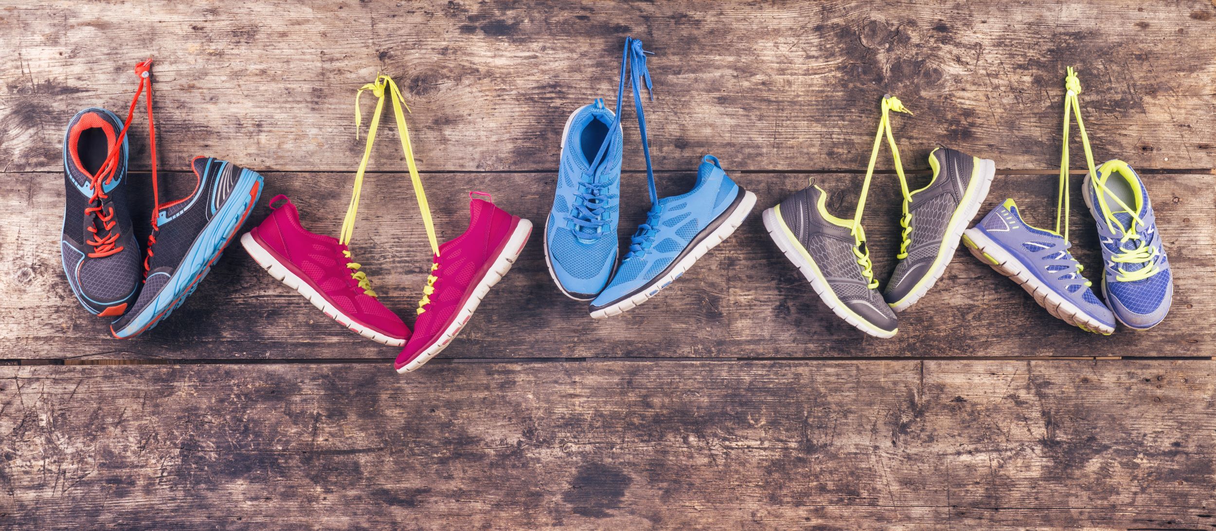 Colorful running shoes hanging on a wooden background.
