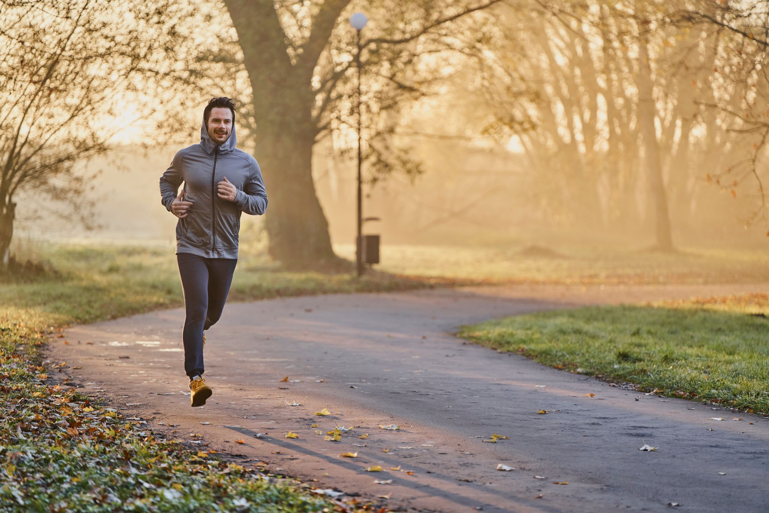 A man is jogging in the park at sunrise.