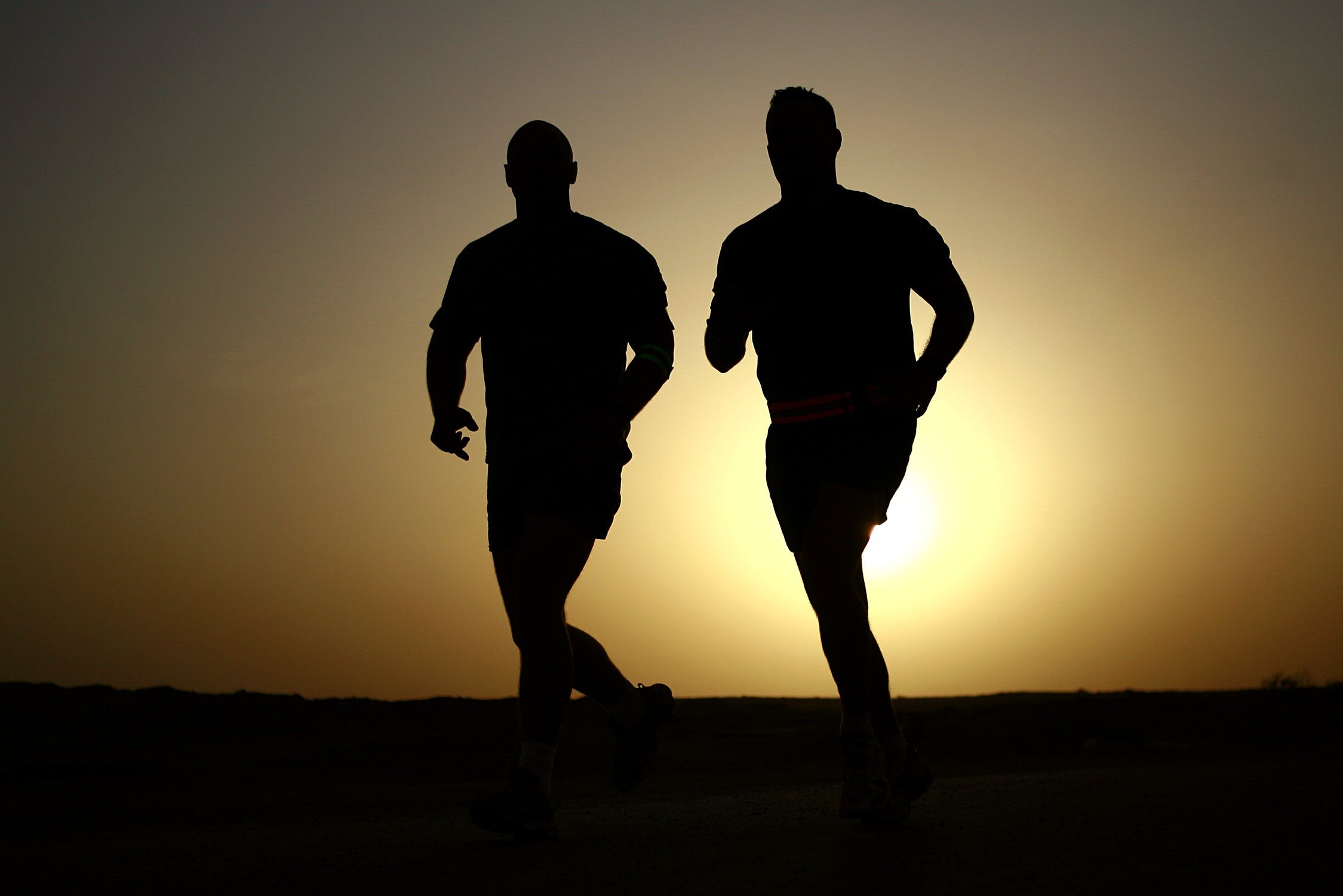 Two men jogging at sunset.