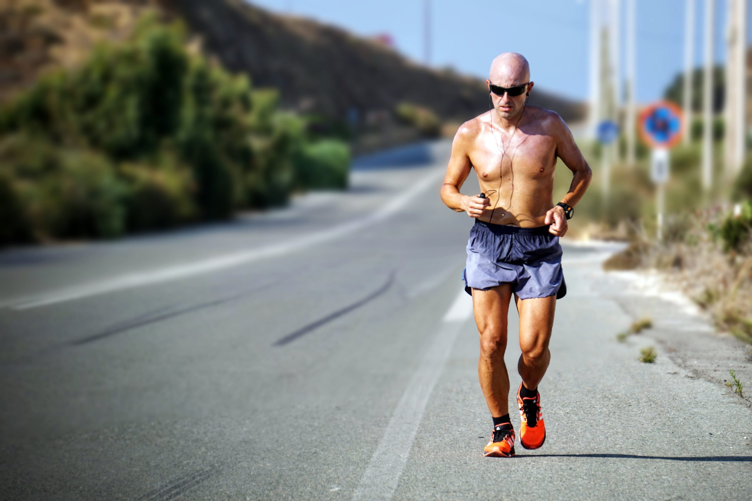 Man running on a sunny day along a roadside.