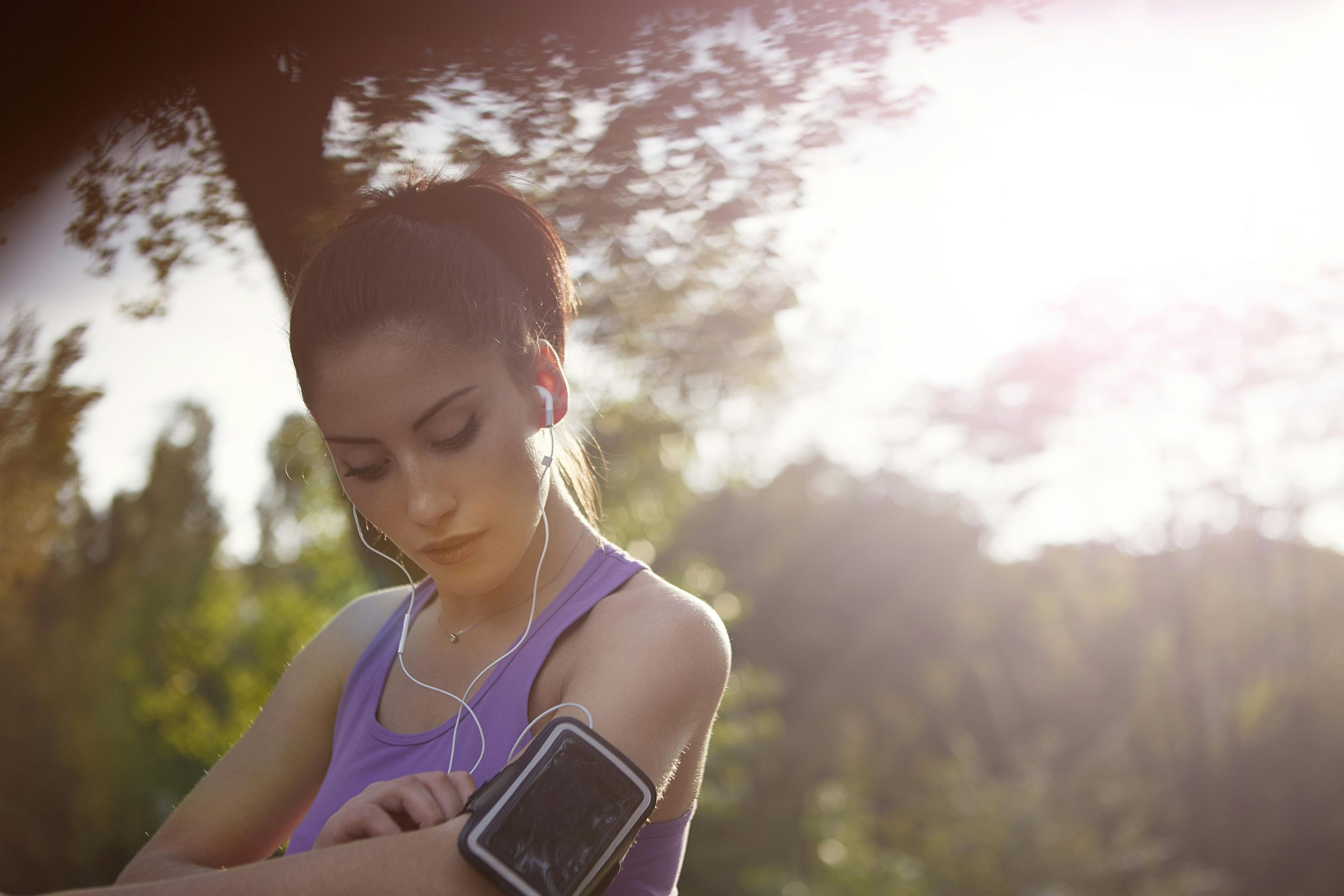 Woman checking her fitness tracker during an outdoor workout at sunset.