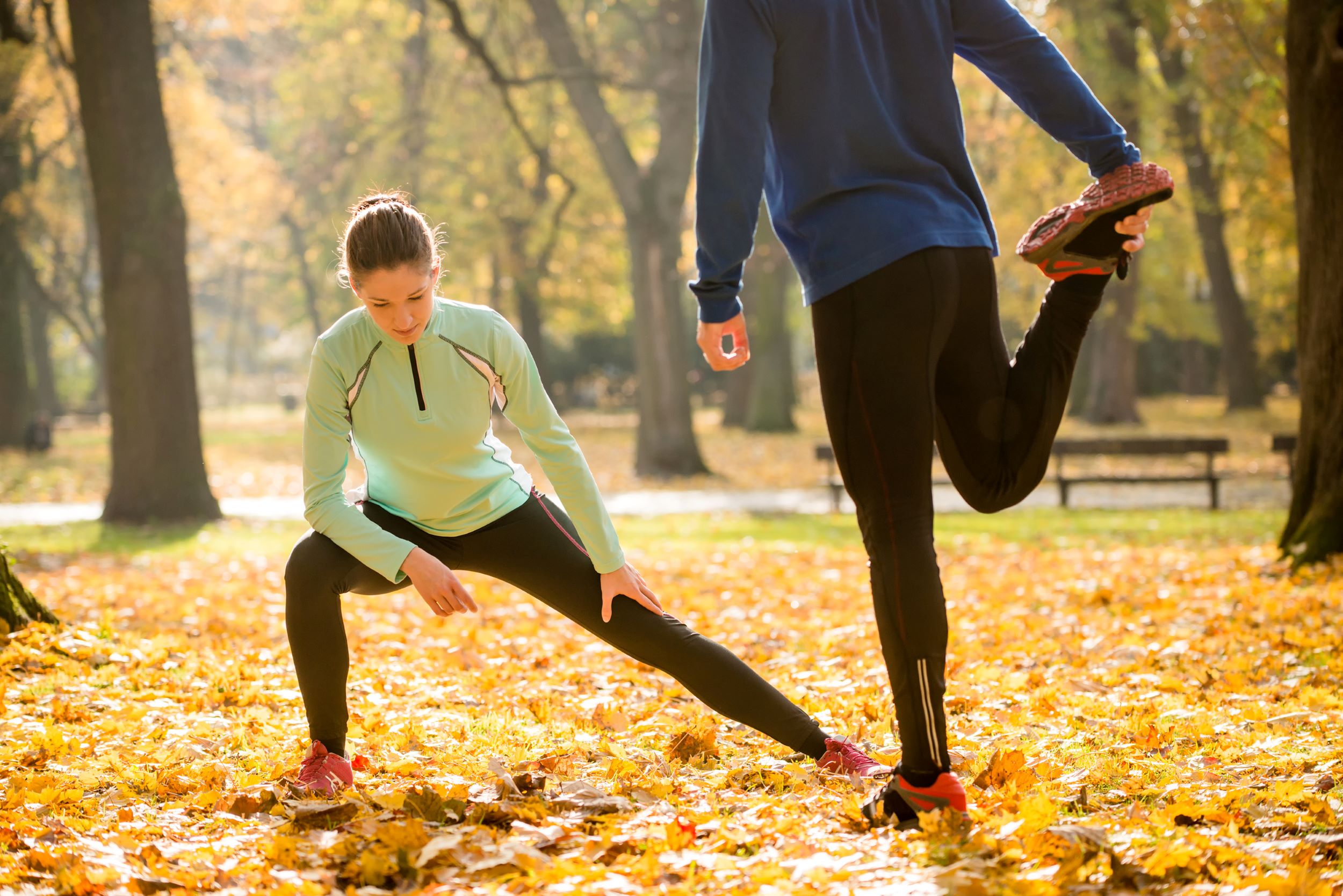 A man and woman stretching in the park.